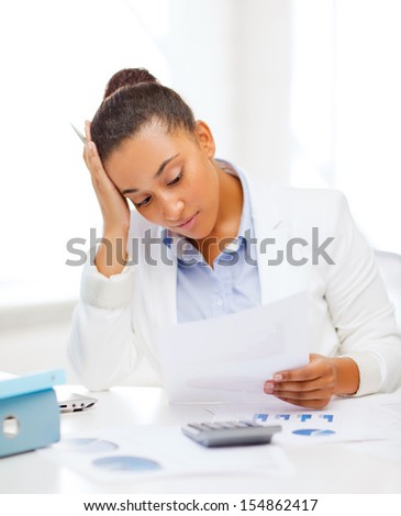 business and tax concept - african businesswoman working with calculator in office