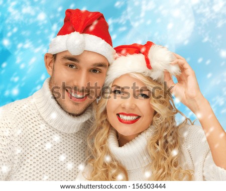 christmas, x-mas, winter, happiness concept - family couple in sweaters and santa\'s hats