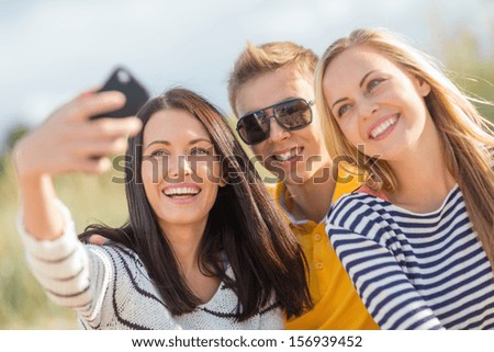 Summer, Holidays, Vacation, Happy People Concept - Group Of Friends Taking Photo Picture With Smartphone