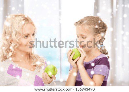 family, children, christmas, x-mas, love concept - mother and daughter holding green apples