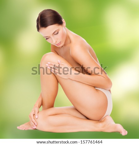 health and beauty, eco, bio, nature concept - beautiful naked woman touching her legs