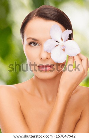 health and beauty, eco, bio, nature concept - relaxed woman with orchid flower over eye