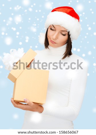 christmas, x-mas, winter, happiness concept - suspicious woman in santa helper hat with gift box