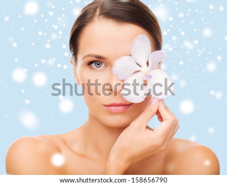 health and beauty concept - relaxed woman with orchid flower over eye