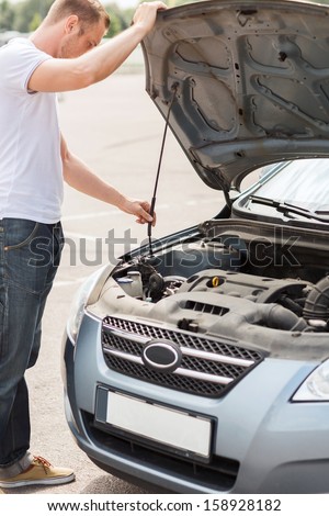 transportation and vehicle concept - man opening car bonnet and looking under hood