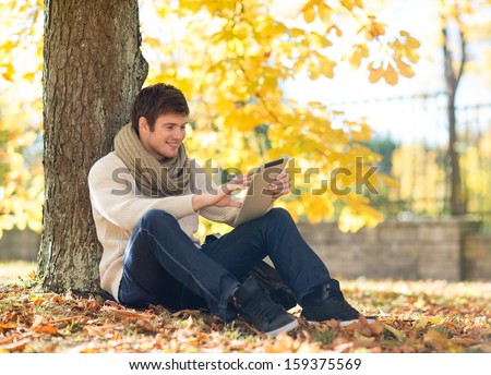 business, communication, modern technology and leisure concept - man with tablet pc in autumn park