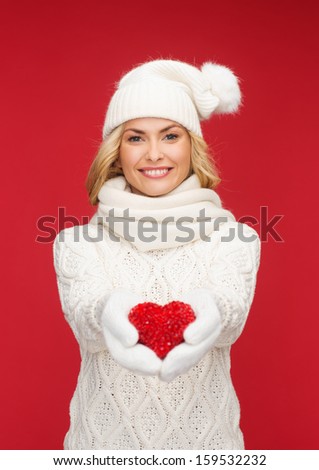 christmas, x-mas, winter, charity, love, happiness concept - smiling woman in winter clothes with red heart