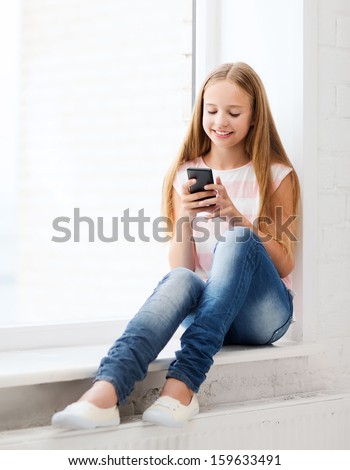 education, school, technology and internet concept - little student girl with smartphone at school