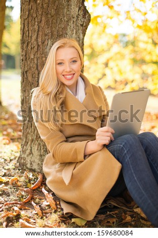 business, communication, modern technology and leisure concept - woman with tablet pc in autumn park