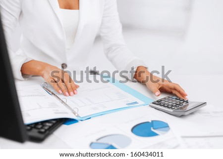 business, office, tax, school and education concept - woman hand with calculator and papers