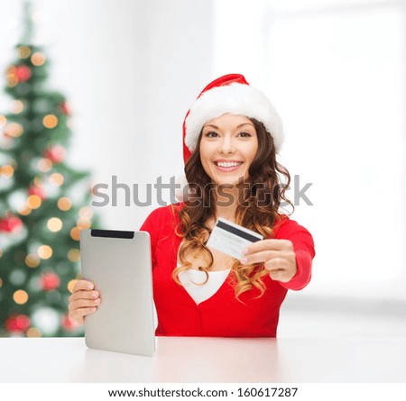 christmas, x-mas, online shopping concept - woman in santa helper hat with gift box, tablet pc computer and credit card