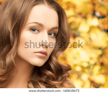 health and beauty concept - face of beautiful woman with long hair over yellow autumn leaves background