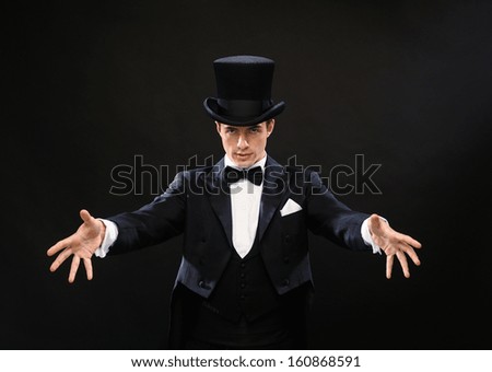 magic, performance, circus, show concept - magician in top hat showing trick