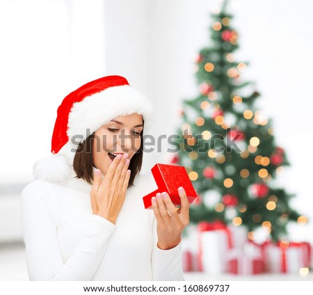christmas, x-mas, winter, happiness concept - surprised woman in santa helper hat with small gift box