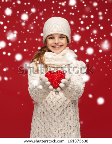 seasonal, people, happiness , health, charity, love concept - smiling teenage girl in winter clothes with small red heart