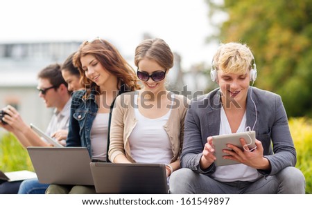 Summer, Internet, Education, Campus And Teenage Concept - Group Of Students Or Teenagers With Laptop And Tablet Computers Hanging Out