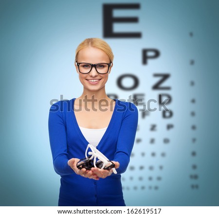 vision and health concept - smiling woman in casual clothes wearing and holding eyeglasses