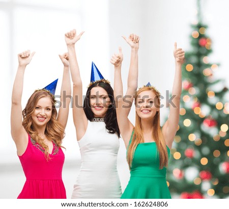 celebration, friends, bachelorette party, birthday concept - three smiling women wearing blue hats and showing thumbs up