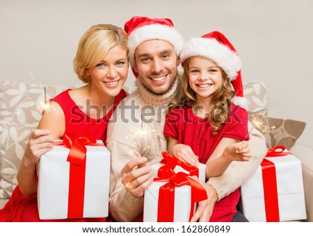 family christmas x-mas winter happiness and people concept smiling family in santa helper hats with many gift boxes and bengal lights family christmas x-mas winter happiness and people concept smiling family in santa helper hats with many gift boxes and bengal lights