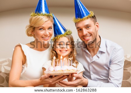 celebration, family, holidays and birthday concept - happy family in blue hats with cake
