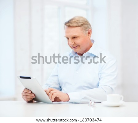 business, office, oldness, school and education concept - old man wearing eyeglasses with tablet pc computer at home