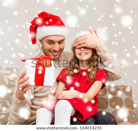 family, christmas, x-mas, winter, happiness and people concept - smiling father surprise daughter with gift box covering eyes with hand