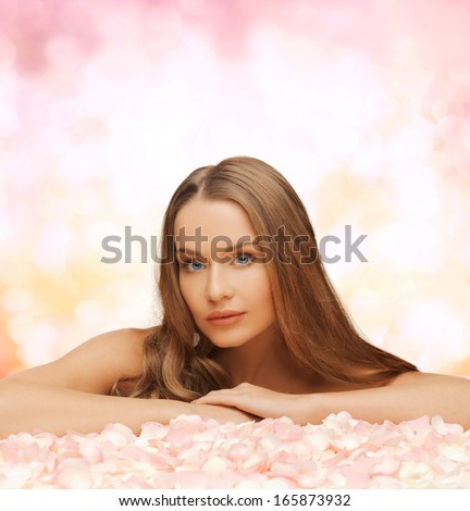 health and beauty concept - beautiful woman with long hair and rose petals