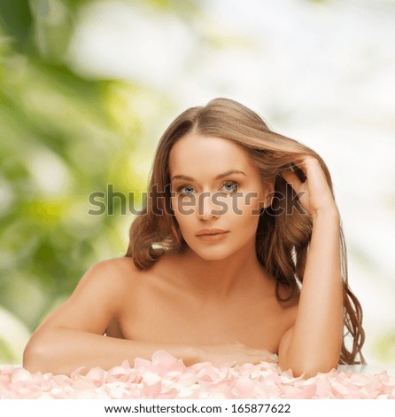 health and beauty concept - beautiful woman with rose petals and long hair