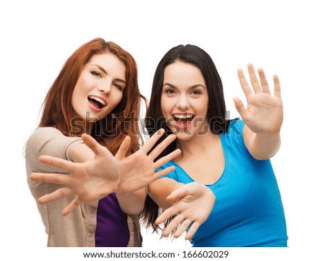 happiness and people concept two smiling girls showing their palms happiness and people concept two smiling girls showing their palms