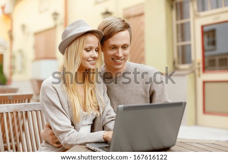 summer holidays, city, dating and technology concept - smiling couple with laptop computer in cafe