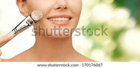 beauty amd make-up concept - closeup picture of beautiful woman with brush applying cream foundation