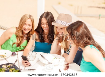 Summer Holidays, Vacation And Technology Concept - Girls Looking At Smartphone In Cafe On The Beach