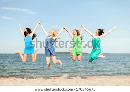 summer holidays and vacation concept - smiling girls jumping on the beach