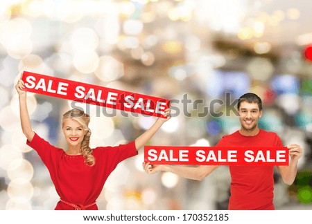 shopping, sale, mall and christmas concept - smiling woman and man with red sale signs at shopping mall