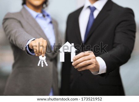 Business, Eco, Real Estate And Office Concept - Businessman And Businesswoman Holding White Paper House And Keys In Office