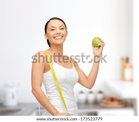 beautiful sporty woman with apple and measuring tape