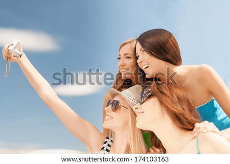 summer holidays and vacation concept - smiling girls taking selfie with digital camera in cafe on the beach