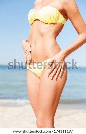 beach, vacation, summer holidays and body concept - closeup of female body in bikini at beach