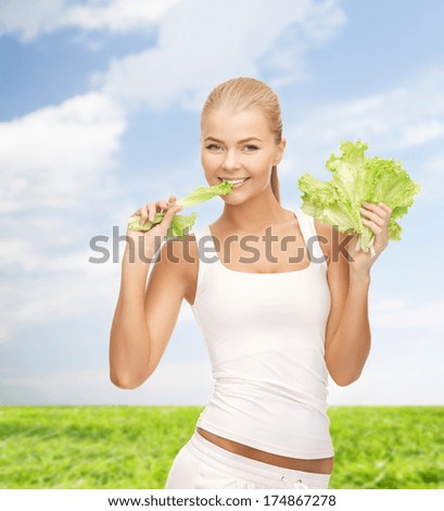 fitness and diet concept - picture of healthy woman biting piece of lettuce