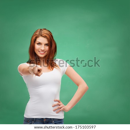 gestures and people concept - happy teenager in blank white t-shirt pointing at you