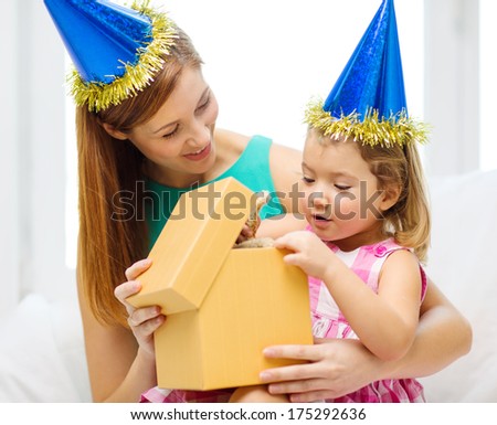 family, children, celebration, holidays, birthday and happy people concept - happy mother and daughter in blue hats with gift box