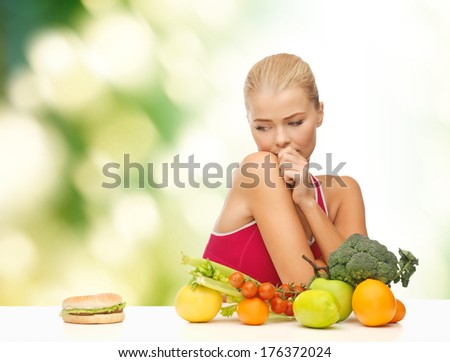 fitness, diet, health and food concept - doubting woman with fruits and hamburger
