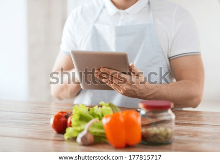 cooking, technology and home concept - closeup of man reading recipe from tablet pc computer