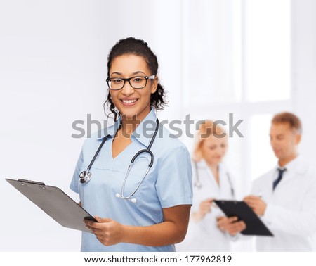 healthcare and medicine concept - smiling female african american doctor or nurse in eyeglasses with stethoscope and clipboard