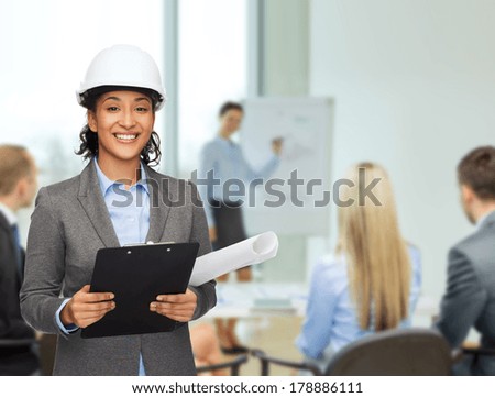 building, developing, consrtuction and architecture concept - smiling businesswoman in white helmet with clipboard and blueprint at office