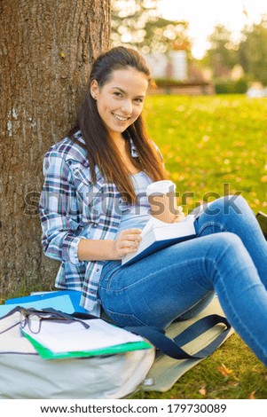 education, campus and people concept - smiling teenager reading book with take away coffee