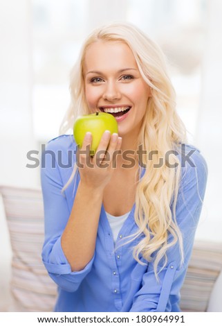 diet, health and home concept - smiling yoing woman with green apple at home