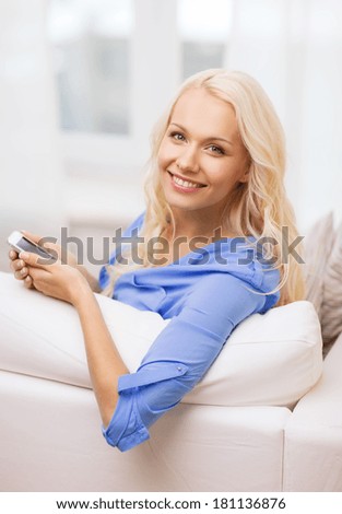home, technology and internet concept - smiling woman with smartphone lying on couch at home