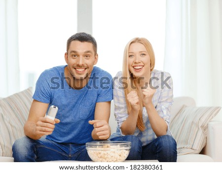 food love family sports entretainment and happiness concept smiling couple with popcorn cheering sports team at home food love family sports entretainment and happiness concept smiling couple with popcorn cheering sports team at home