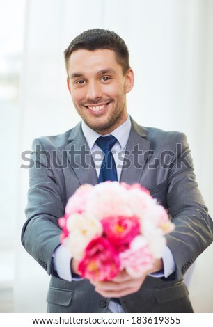 spring, flowers and happiness concept - smiling handsome man giving bouquet of fresh flowers